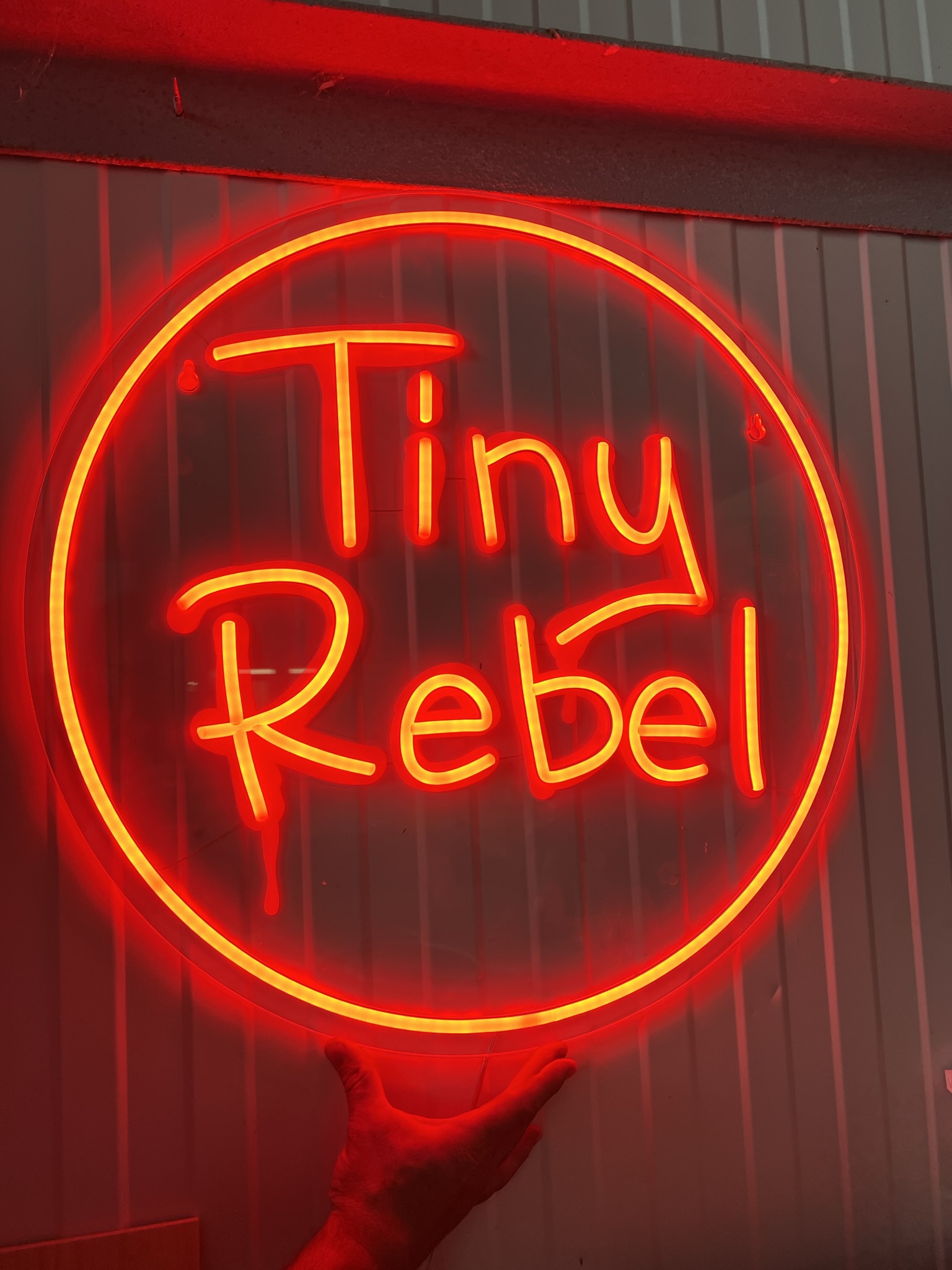 Tiny Rebel red round neon held in workshop